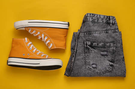 Gumshoes and jeans on yellow background. Women's clothing and footwear. top viewの写真素材