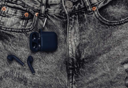Wireless headphone charging case hanging on gray jeans