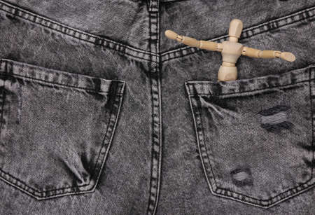 Wooden puppet in the pocket of gray jeansの写真素材