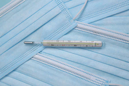 Thermometer and facial masks on a blue background. medicine conceptの写真素材
