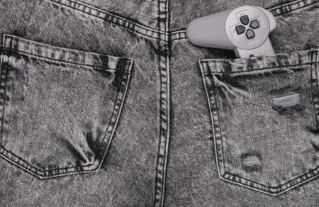 Retro gamepad in back pocket of gray jeans