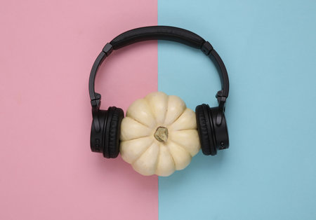 Mini white pumpkin with stereo headphones on pink blue backgroundの写真素材