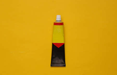 Tube of glue on a yellow background. top view
