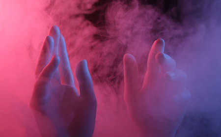 Mannequin Hands in dense smoke with red-blue neon light.の写真素材