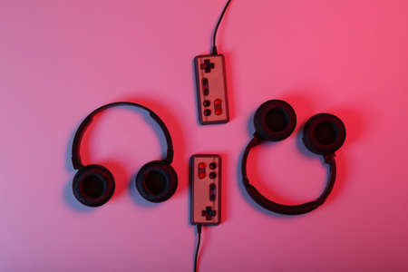 Stereo headphones with retro gamepads in red blue neon light. Time to play. video game. gaming conceptの写真素材
