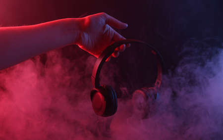 Hand holding clock in dense smoke with red-purple neon light.の写真素材