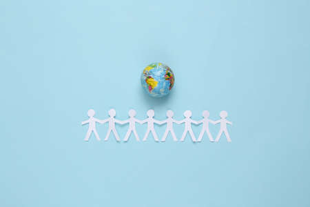 Cut paper human chain hold hands around the globe and show their unity on blue background....