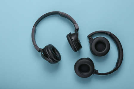 Two pairs of black wireless stereo headphones on a blue background
