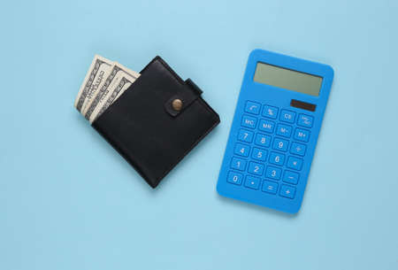 Leather wallet with one hundred dollar bills and calculator on blue background. saving moneyの写真素材