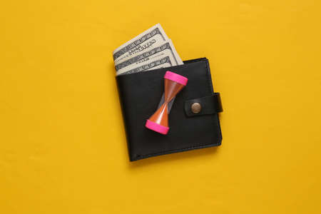 Time is money. Leather wallets with hourglass on yellow background.の写真素材