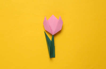 Pink paper tulip on yellow background. March 8, women's day concept. Handmade origami tulip. top view. minimalismの写真素材