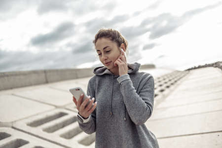 Sporty attractive woman using smartphone and listening to music in headphones outdoorsの写真素材