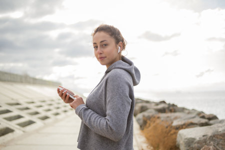 Sporty attractive woman using smartphone and listening to music in headphones outdoorsの写真素材