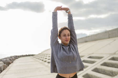 Attractive sporty woman in sportswear trains outdoors. Warm up or stretching, healthy lifestyle.の写真素材
