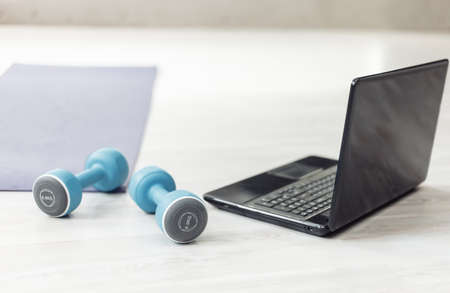 Dumbbells on floor with laptop and fitness mat. Fitness tutorial, sport equipment. Weight loss, healthy lifestyle conceptの写真素材