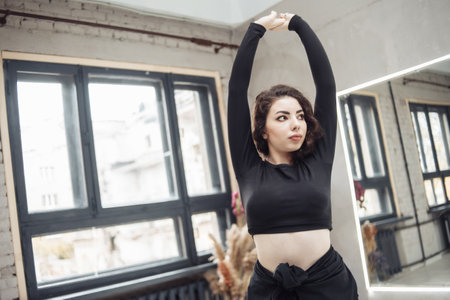 Young attractive brunette woman practicing hand stretching before indoor workoutの写真素材