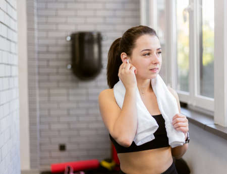 Portrait of young fitness woman with towel on shoulders indoorsの写真素材
