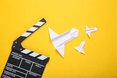 Clapperboard and origami rockets on a yellow background. science fiction film. top view