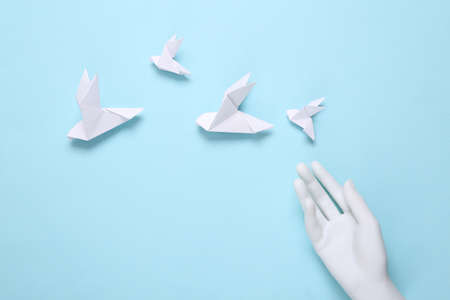 Origami pigeons and hand on blue background. peace symbolの写真素材