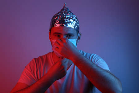 Bearded Man in foil hat and medical mask in blue red neon light. Conspiracy. conspiracy theoryの写真素材