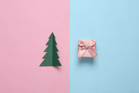 Paper cut christmas tree and gift box on blue pink pastel backgroundの写真素材
