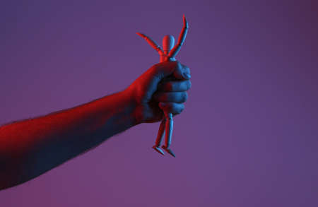 Puppeteer hand holding wooden puppet in red blue neon lightの写真素材