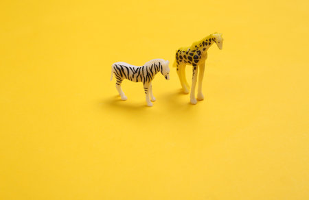 Zebra and giraffe figurines on yellow backgroundの写真素材
