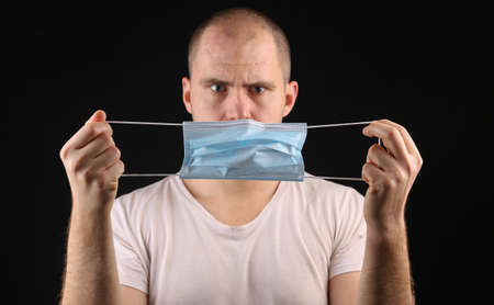 Young man with medical mask on black backgroundの写真素材
