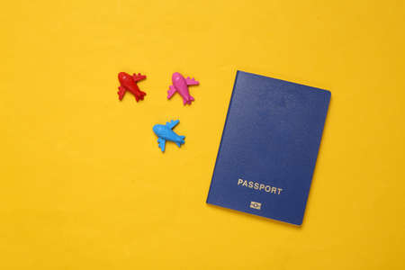Many colored toy airplanes and passports on yellow background. travel concept