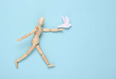 Wooden puppet with Origami dove on blue backgroundの写真素材