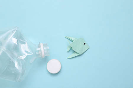 Eco, save the planet, plastic ocean pollution concept. Origami fish with plastic bottle on blue backgroundの写真素材
