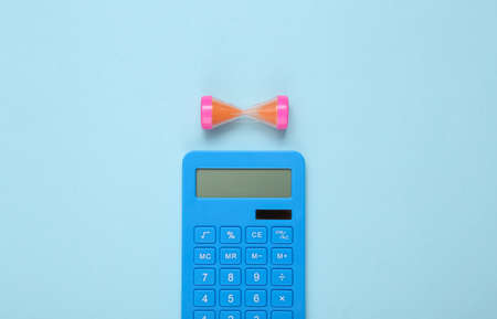 Calculator and hourglass on a blue background. Income calculation, investment, depositの写真素材
