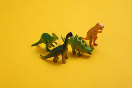 Toy dinosaurs on yellow backgroundの写真素材