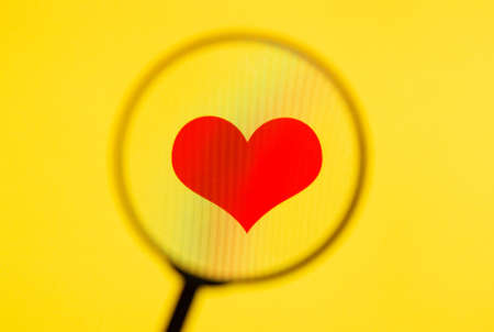 Red heart on yellow screen through magnifying glass.の写真素材