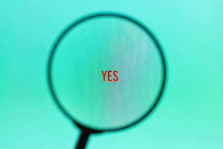 Word yes on blue screen through magnifying glass.の写真素材