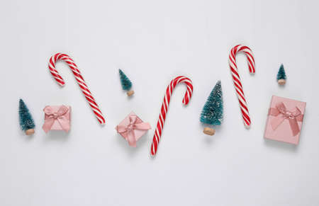 Christmas striped candy canes, gift boxes and mini Christmas trees on white background. new year, xmas backgroundの写真素材