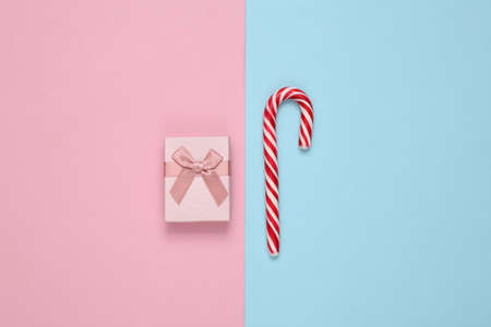 Christmas striped candy cane and gift box on blue pink background.の写真素材