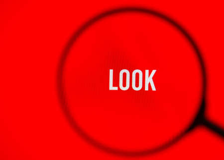 Word look on red screen through magnifying glass.の写真素材