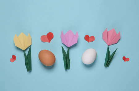 Origami tulips, eggs and hearts on blue background. Spring, easter concept