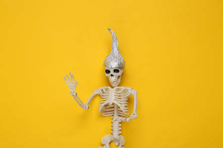Skeleton in foil hat on yellow background. Conspiracyの写真素材