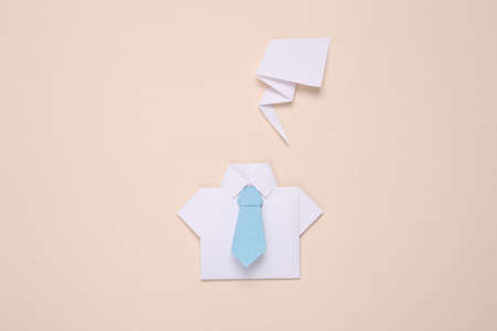 Origami shirt with tie and dialog cloud on beige background. business concept