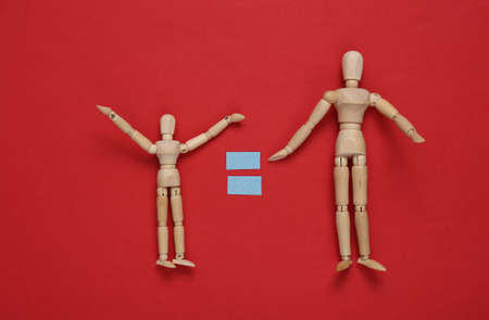 Equality. Two wooden puppets with equal sign on a red background