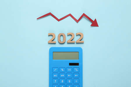 Economic crisis 2022. Arrow falling, calculator and 2022 on blue background