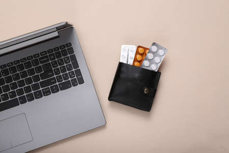 Wallet with blister of pills and laptop on beige backgroundの写真素材