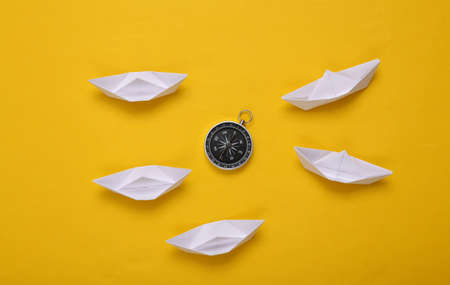 Origami paper boats and compass on yellow backgroundの写真素材
