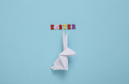 Origami rabbit and the word easter on blue background. Easter, spring compositionの写真素材