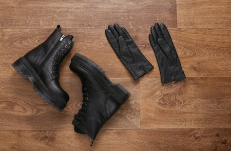 Black Leather boots and gloves on wooden floor. top view. flat layの写真素材