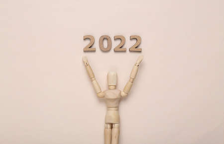 Wpdden puppet with 2022 on beige background. new year