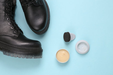 Leather footwear care. Boots and bottle of shoe polish on blue backgroundの写真素材