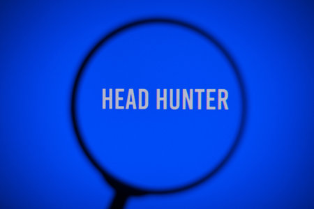 Inscription head hunter on blue screen of the monitor through magnifying glassの写真素材